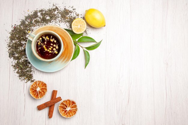 Top view herbal tea white cup of herbal tea next to the herbs lemon cinnamon on the white table