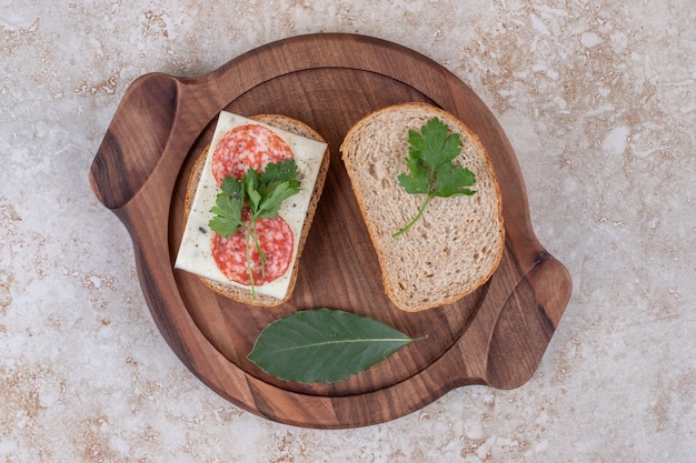 Free photo top view of homemade salami sandwiches on wooden tray.