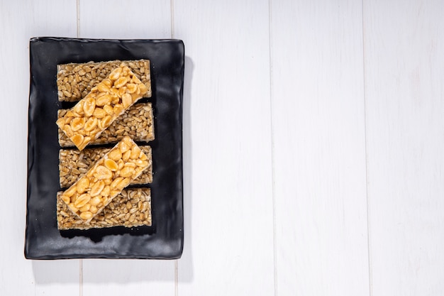 Free photo top view of honey bars with peanuts and sunflower seeds on a black platter with copy space on rustic