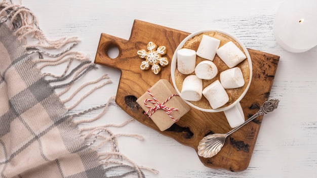 Top view of hot cocoa and marshmallows in cup with spoon and blanket