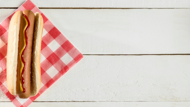 Top view hot dog with napkin on wooden background