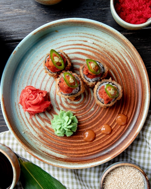 Free Photo top view of hot fried sushi rolls with wasabi and ginger on a plate on wood