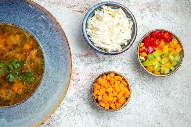 Top view hot vegetable soup with sliced vegetables on white space