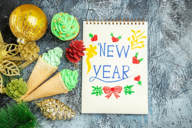 Top view ice creams xmas with new year written on notebook on grey background