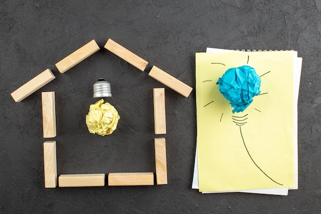 Top view idealight bulb in house shaped wood blocks idealight bulb on notepad on black