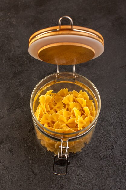 A top view italian dry pasta yellow raw inside bowl isolated on the dark