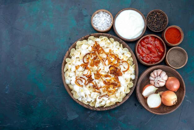 Top view italian pasta with different seasonings on dark