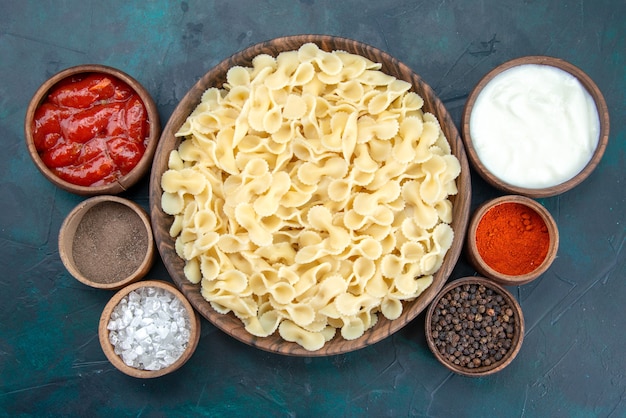 Top view italian pasta with different seasonings on dark