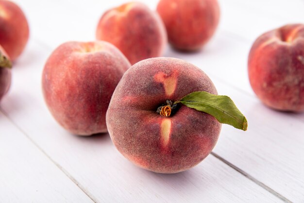 Top view of juicy delicious and fresh peaches with leaves isolated on a white surface