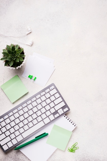 Top view of keyboard on desk with succulent plant and sticky notes