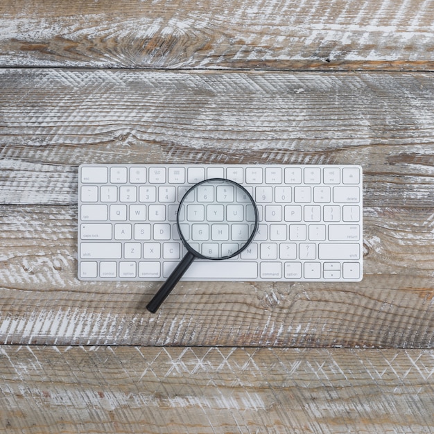 Free Photo top view keyboard with magnifier on wooden background. vertical