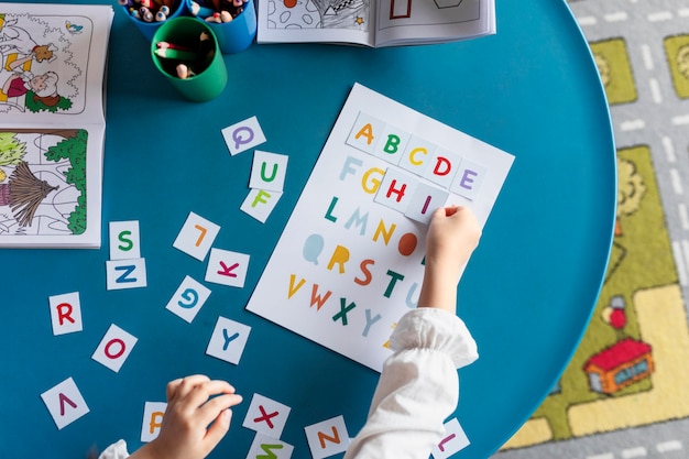 Top view kid learning letters at kindergarten