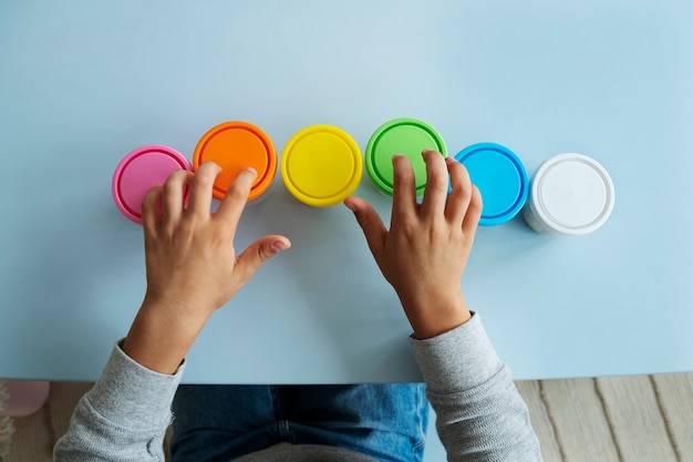 Free photo top view kid with playdough containers