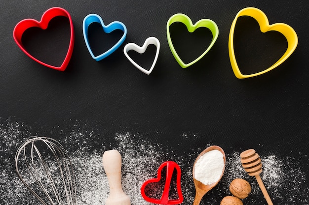 Free photo top view of kitchen utensils with colorful heart shapes and flour