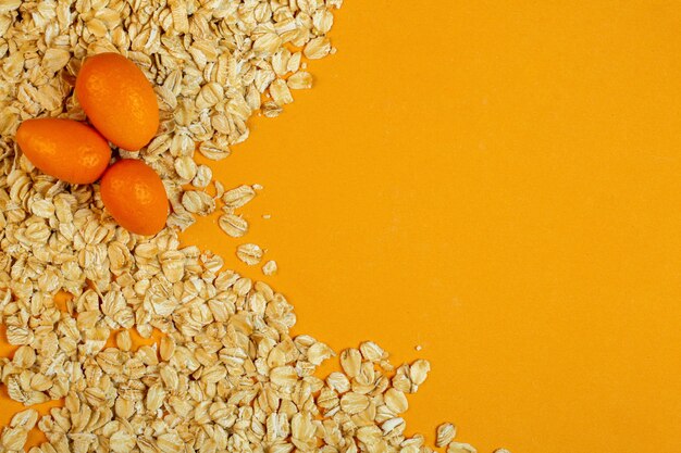 Top view of kumquat on oat flakes with copy space on yellow jpg