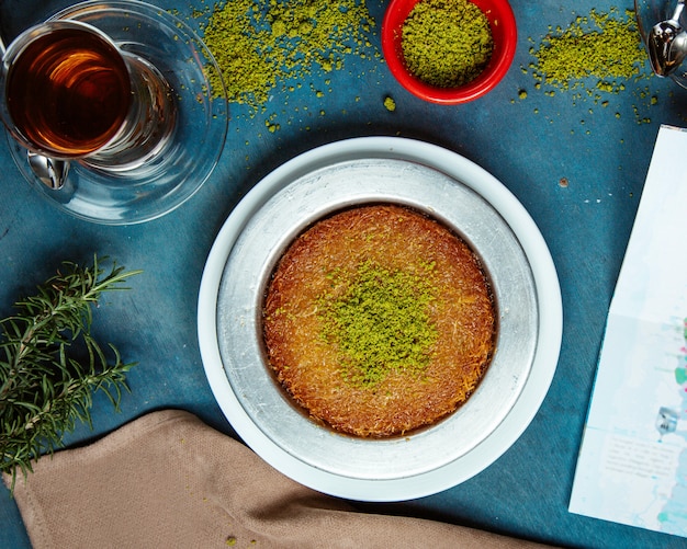 Free photo top view of kunefe dessert garnished with pistachio served with black tea