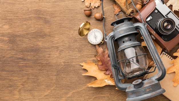 Free photo top view of lantern with camera and autumn leaves