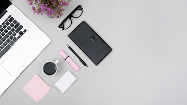 Top view of laptop with coffee cup and stationery on gray background