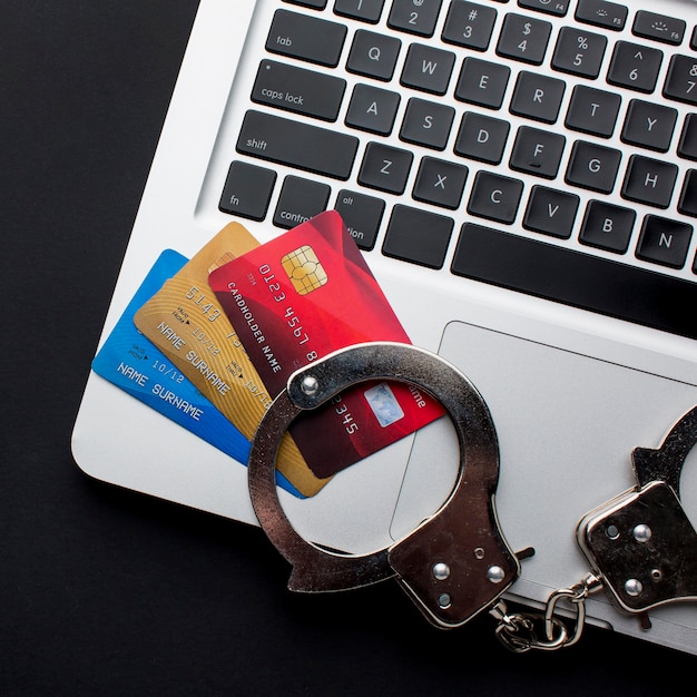 Free Photo top view of laptop with credit cards and handcuffs