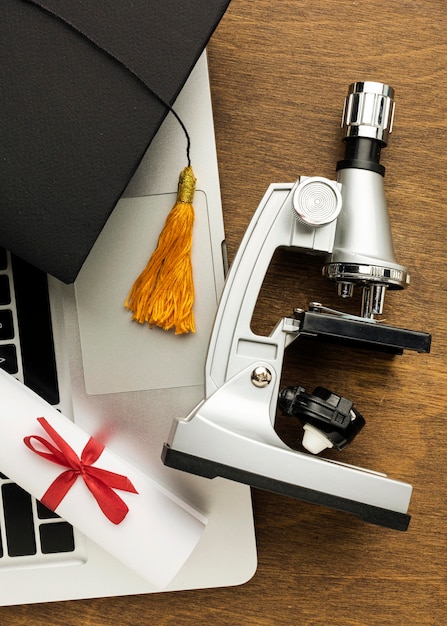 Free Photo top view of laptop with microscope and academic cap