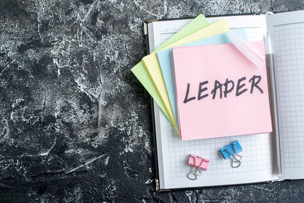 top view leader written note with stickers and copybook on gray background