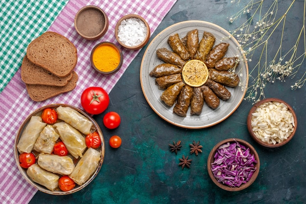 Top view leaf dolma eastern meat meal rolled inside green leaves with bread and cabbage dolma on dark-blue desk meat dinner dish eastern meal