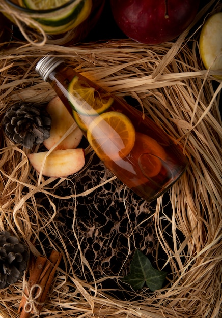 Top view lemon tea with lime sliced red apple cinnamon and fir cone on the straw