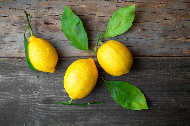 Free photo top view lemons with leaves on dark wooden background. horizontal