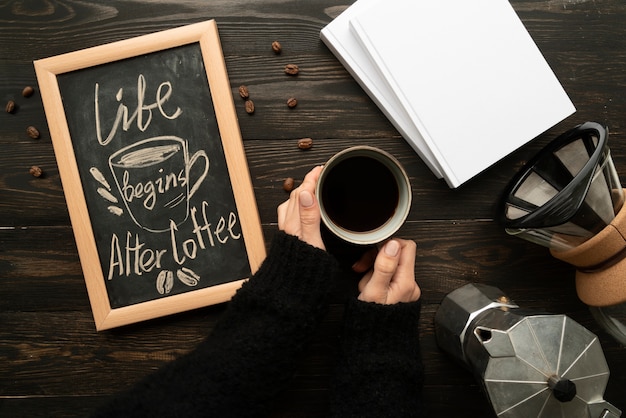 Free photo top view of life begins after coffee inspirational quote on chalkboard with woman holding coffee