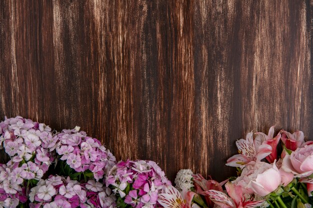 Top view of light pink flowers with lilies and roses on a wooden surface