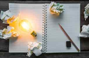 Free photo top view of lit light bulb on a notebook