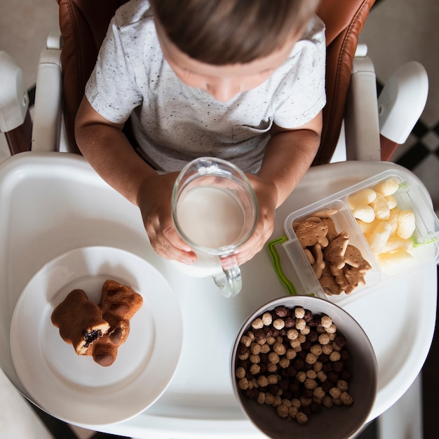 Free photo top view little boy with assortment of snacks