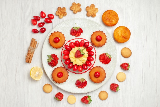 Top view little cakes with fruits inside plate on white desk