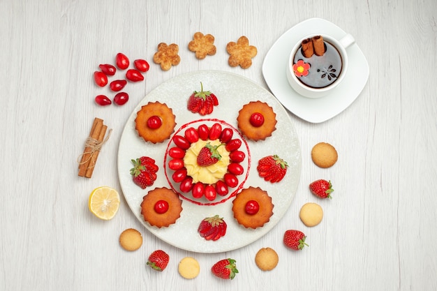 Top view little cakes with fruits inside plate on white floor