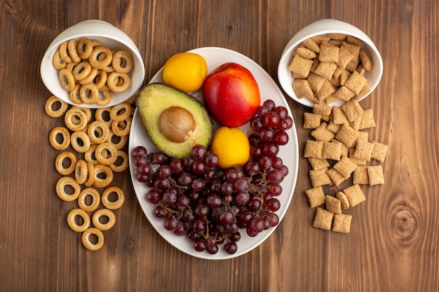 Free Photo top view little cookies and crackers with fruits on brown wooden desk