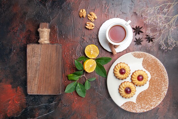 Top view little cookies with cup of tea on dark table sugar biscuit cake