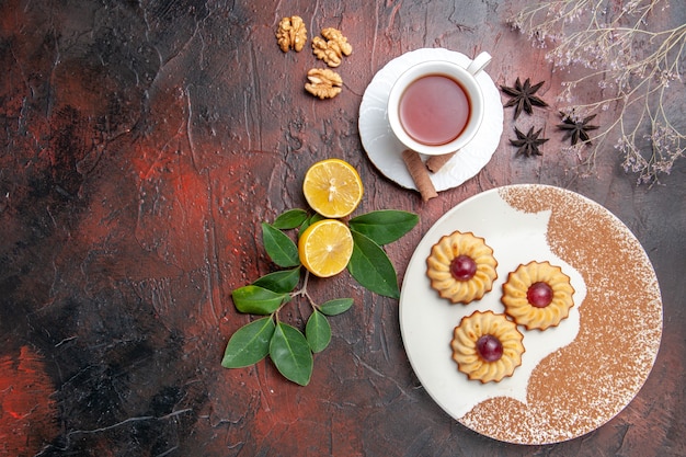 Top view little cookies with cup of tea on dark table sugar biscuits cake sweet