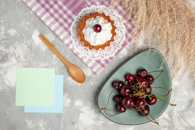 Top view little creamy cake with fresh sour cherries on the light background fruit cake sweet bake cream