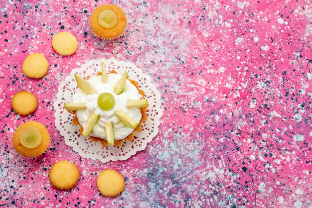 Top view little creamy cake with sliced fruits cookies on the colored desk cake sweet sugar color photo