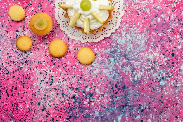 Top view little creamy cake with sliced fruits cookies on the colorful desk cake sweet sugar color photo