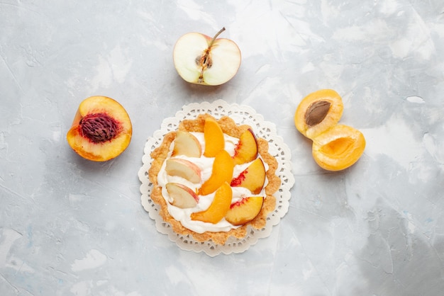 Free photo top view little creamy cake with sliced fruits and white cream on the white-light table fruit cake sweet biscuit cookie bake