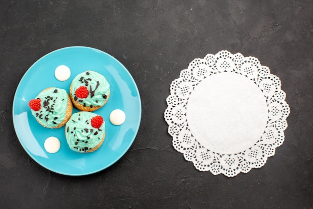 Free photo top view little creamy cakes delicious sweets for tea inside plate on a dark-grey surface tea cream cake biscuit dessert color