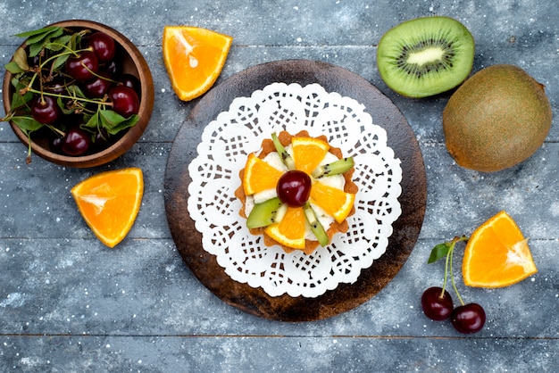 A top view little delicious cake with cream and fresh sliced fruits on the grey desk cake sugar tea 