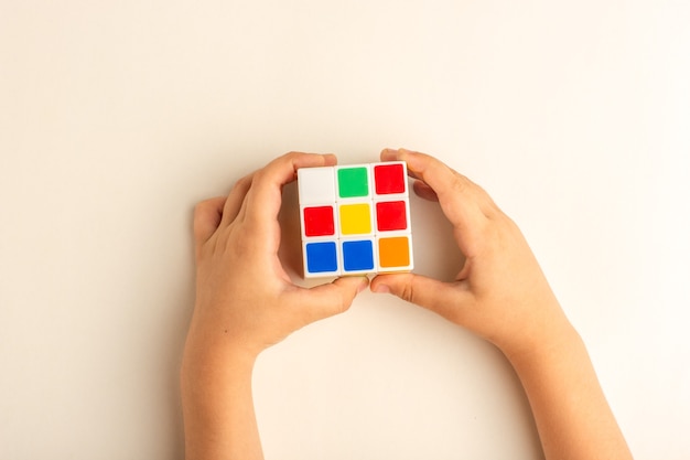 Free Photo top view little kid playing with rubics cube on white desk