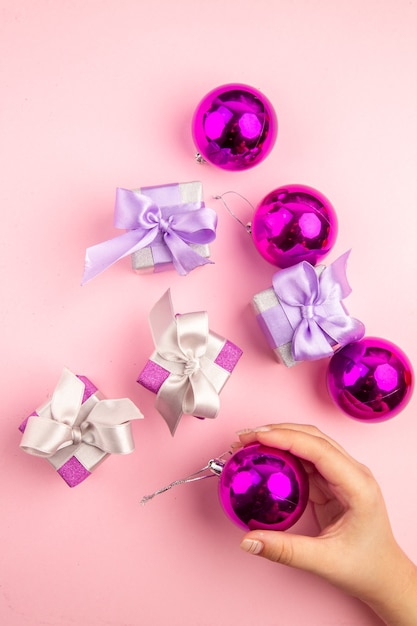 Top view of little presents with xmas tree toys on pink surface