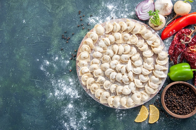 Top view little raw dumplings with flour and vegetables on dark background meat dough food dish calorie color bake vegetable meal