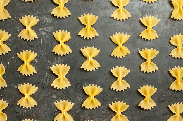 Free photo top view little raw pasta spread all over dark-grey background