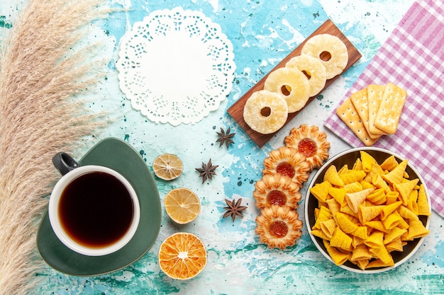 Free photo top view little spicy chips with crackers tea dried pineapple rings and cookies on blue surface chips snack color crisp calorie