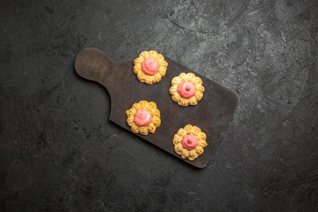 Top view of little sugar cookies with strawberry cream on a grey surface