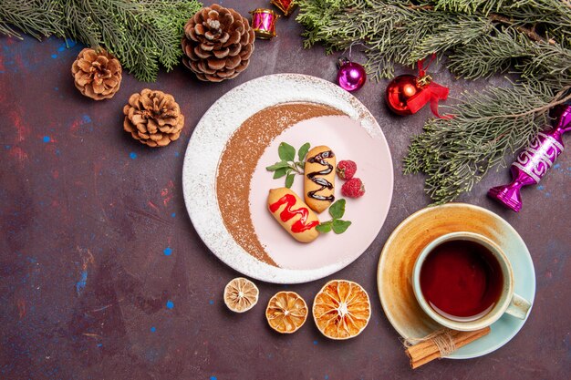 Top view of little sweet biscuits with cup of tea on black